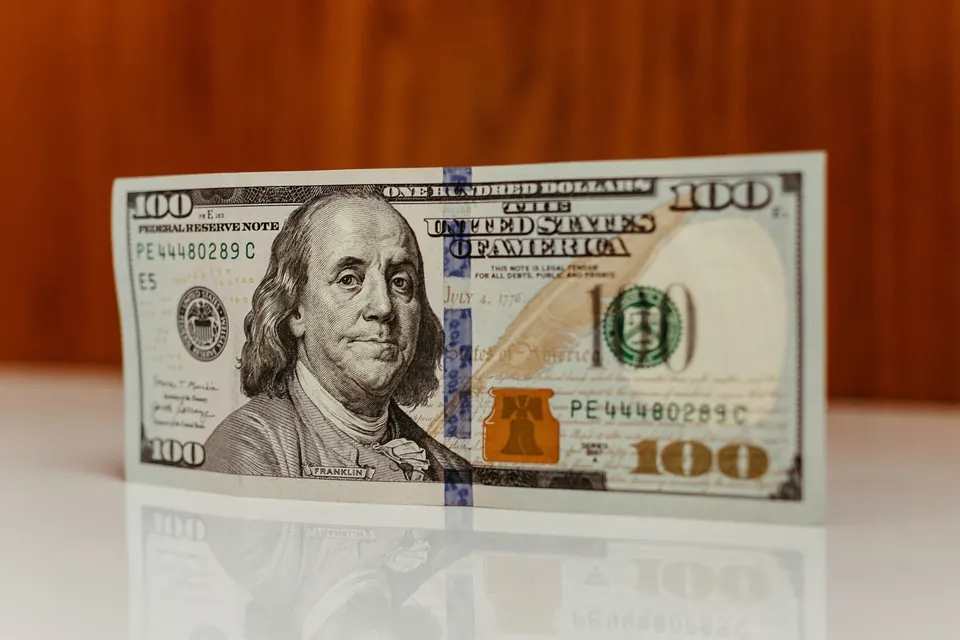 U.S. 100-dollar bill standing on a reflective table