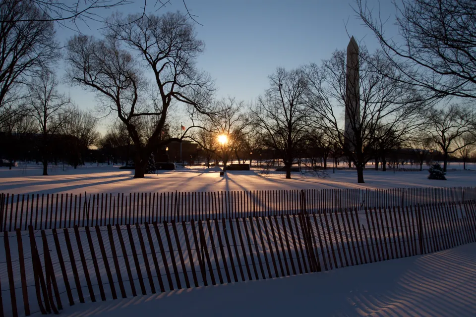 Washington Monument beyond snow-covered grounds at sunrise